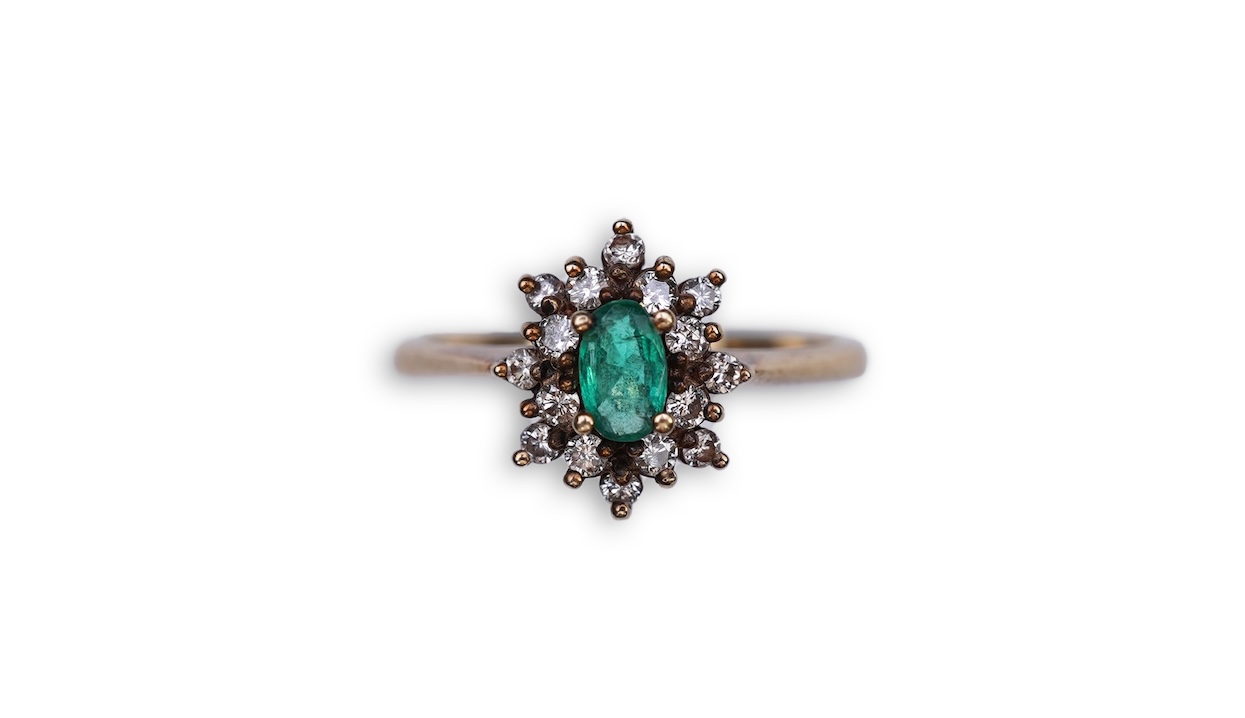 An emerald and diamond cluster ring